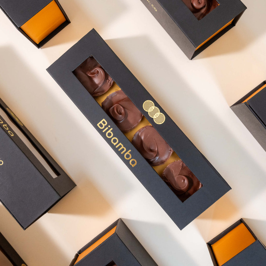 A top-down view of a black rectangular gift box containing four Bibamba peanut butter cups, available in dark or milk chocolate
