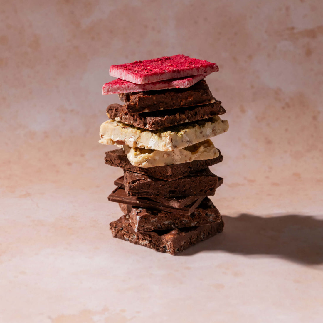 A vertical stack of 12 assorted milk and white chocolate squares, featured in Bibamba's Milk & White Chocolate Sampler box.