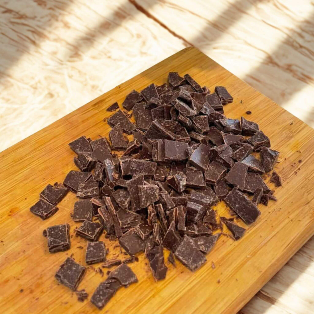 Hand-cut milk chocolate pieces on a wooden cutting board, ready for baking